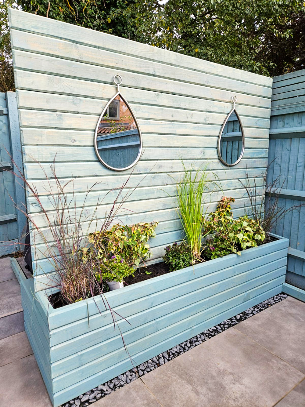 Sage green painted horizontal fence with mirrors and built-in planter box