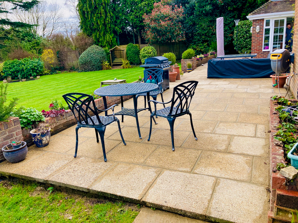 Large cream sandstone patio slabs in geometric pattern with garden furniture
