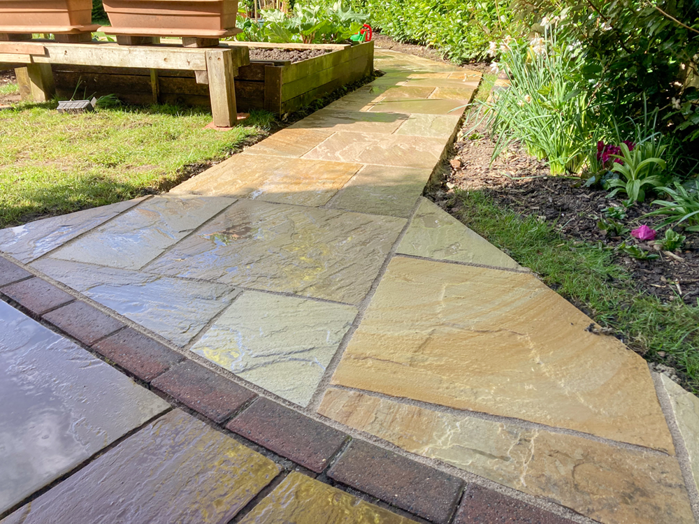 Natural stone pathway with diagonal corner details and brick edging through garden