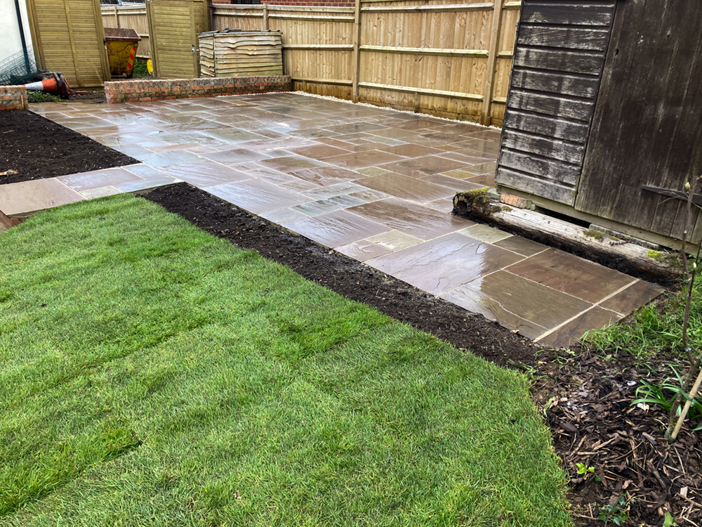 Indian sandstone patio in brown and grey tones with landscaped borders